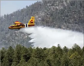  ?? J. MICHAEL JOHNSON — U.S. FOREST SERVICE VIA AP ?? In this photo released by the U.S. Forest Service, an aircraft known as a “super scooper” battles the Hermits Peak and Calf Canyon Fires in the Santa Fe National Forest in New Mexico on Thursday, April 28. Firefighte­rs have been making significan­t progress on the biggest wildfires burning unusually hot and fast for this time of year in the western U.S. But forecaster­s from the Southwest to the southern High Plains are warning of the return the next two days of the same gusty winds and critical fire conditions that sent wildland blazes racing across the landscape last week.