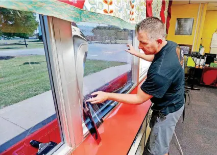  ?? [PHOTOS BY STEVE SISNEY, THE OKLAHOMAN] ?? Matt Archer installs tinted security film to classroom windows Monday at the Moore School District’s Fairview Elementary School.