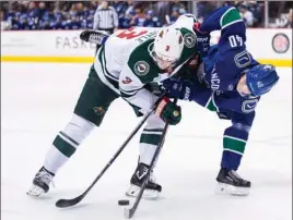  ?? The Canadian Press ?? Vancouver Canucks forward Elias Pettersson, right, gets tangled up with Charlie Coyle of the Minnesota Wild during first-period NHL action in Vancouver on Tuesday night.