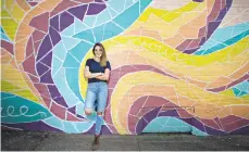  ??  ?? Sarah Lanier stands in front of one of her murals Wednesday in Bangor.