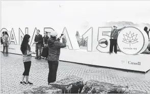  ?? METROLAND FILE PHOTO ?? Tourists take photos of the Canada 150 sign at Table Rock overlookin­g the Horseshoe Falls in Niagara Falls, Ont., last spring.