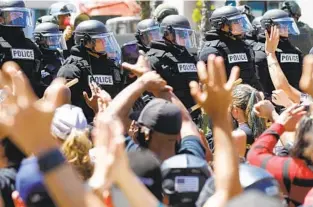  ?? K.C. ALFRED U-T ?? San Diego police in riot gear lined Broadway in Downtown San Diego on May 31 while people gathered to protest the killing of George Floyd, a Black man, by Minneapoli­s police officers.