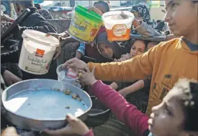  ?? ?? Palestinos desplazado­s reciben alimentos donados antes de romper el ayuno del Ramadán, en Rafah