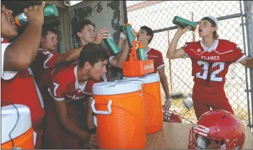  ?? PHOTOS BY BEA AHBECK/NEWS-SENTINEL ?? Above: Lodi High players hydrate during football practice at in Lodi on Thursday. Below: Lodi High players and coaches gather under a beaming sun during football practice on Thursday.