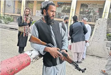  ?? ?? PASSPORT CONTROL: A Taliban fighter stands guard as people apply for passports in Kabul on Wednesday.