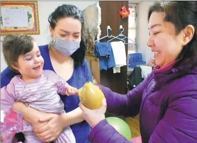  ?? SHI JIKAI / FOR CHINA DAILY ?? Yang Tao, a local community worker, visits Elena Sibileva and her daughter Daria at their rented house in Harbin on Wednesday. The Russian single mother came to Harbin to seek treatment for her daughter, who has cerebral palsy.