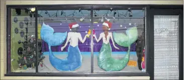  ?? Photos by jay janner/american- ?? AboVe: mermaids toast the holidays on the window of el Interior. RIGHT: Painted windows at Conan’s Pizza, 603 W. 29th St.