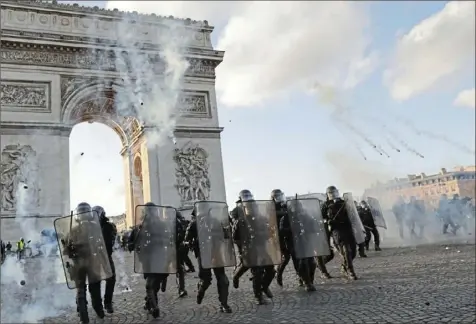  ?? Thomas Samson/AFP/Getty Images ?? Riot police charge using tear gas canisters at the Arc de Triomphe on the Place de l’Etoile in Paris on Saturday, during clashes with Yellow Vest protesters.