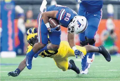  ?? TOM PENNINGTON/GETTY IMAGES ?? UF’s Shawn Davis is brought down by Michigan’s Devin Bush during the second quarter of Saturday’s game at AT&T Stadium.