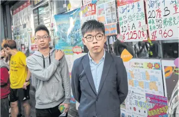  ?? AFP ?? Pro-democracy activist Joshua Wong, centre, queues up to cast his vote during district council elections in Hong Kong in November 2019.