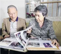  ?? PHOTO: REUTERS ?? United . . . Pham Ngoc Canh and his North Korean wife, Ri Yong Hui, look at their wedding photos at their home in Hanoi.