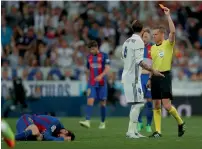  ?? — AP/Reuters ?? Barcelona’s Lionel Messi lies on the ground as Real Madrid’s Sergio Ramos is shown the red card by the referee for fouling the Barcelona striker; Ramos gestures to Barcelona defender Gerard Pique after being sent off and Messi celebrates after scoring...