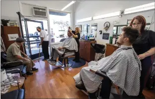  ?? ?? Gonzales, left, visits Bellarmine Barber Shop on Thursday. It's now run by his daughter Esther Faria, center, and granddaugh­ter Stacey Gonzales.