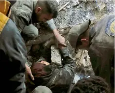  ??  ?? Volunteers of the Syrian Civil Defence, known as the White Helmets, rescue a woman from the rubble of a building after an air strike in Douma, Eastern Ghouta.