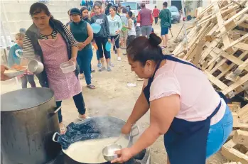  ?? ELLIOT SPAGAT/AP ?? A woman ladles rice and beans for a line of migrants last week at a shelter in Tijuana, Mexico.