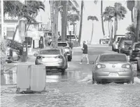  ?? MIKE STOCKER/SOUTH FLORIDA SUN SENTINEL ?? A car drives through salt water flooding the street due to king tides at Taylor Street and A1A in Hollywood on Wednesday.