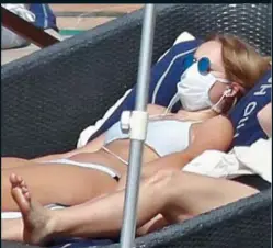  ??  ?? BIZARRE: A sunbather in bikini – and mask – in Tenerife