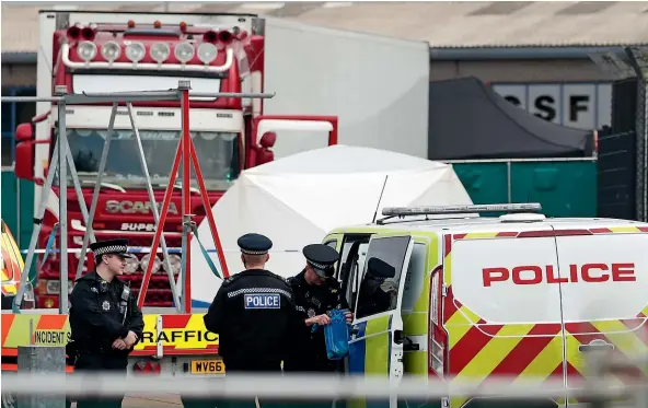  ?? AP ?? Police officers work at the scene where a truck, in rear, was found to contain a large number of dead bodies, in Thurrock, southern England.