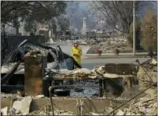  ?? JEFF CHIU - THE ASSOCIATED PRESS ?? Cal Fire forester Kim Sone inspects damage at homes destroyed by fires in Santa Rosa, Calif., Thursday. Gusting winds and dry air forecast for Thursday could drive the next wave of devastatin­g wildfires that are already well on their way to becoming...