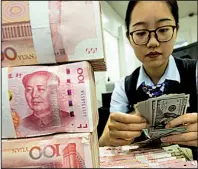  ?? Chinatopix via AP ?? An employee counts U.S. currency next to stack of 100 Chinese yuan notes last week at a bank outlet in Hai’an in eastern China’s Jiangsu province.