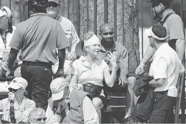  ?? STEPHEN MORTON/THE ASSOCIATED PRESS ?? An unidentifi­ed woman talks with EMS workers after being treated for a head injury after she was hit by Marc Leishman’s shot from the rough on the ninth fairway during the second round of the RBC Heritage golf tournament.