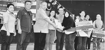  ??  ?? Tiong (third left) presents the prizes to a representa­tive of Kelas Melur of Tabika Perpaduan RPR Kidurong, which emerged winner of a competitio­n run as part of the Jalur Gemilang campaign in Bintulu. Looking on from left are Diana, Herman and Esther.