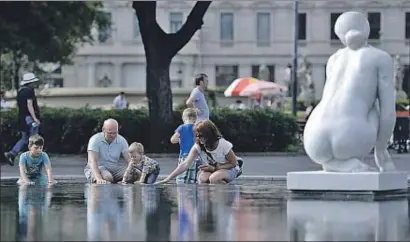  ?? ÀLEX GARCIA ?? Una familia de turistas se refresca en uno de los estanques de la plaza Catalunya en Barcelona