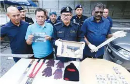  ??  ?? Mazlan (second from right) and his officers showing the guns, machetes and other items seized from the suspects.