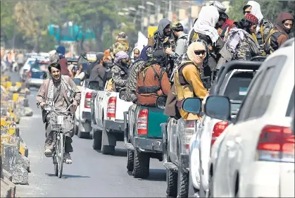  ?? AFP ?? A man rides past a convoy of Taliban members patrolling a street in Kabul, Afghanista­n, on Thursday.