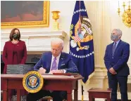  ?? ALEX BRANDON/ASSOCIATED PRESS ?? President Joe Biden signs executive orders after speaking abut the virus, accompanie­d by Vice President Kamala Harris and Dr. Anthony Fauci, director of the National Institute of Allergy and Infectious Diseases.