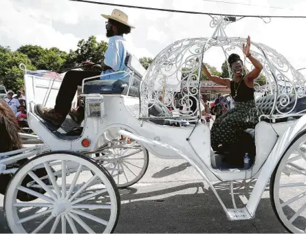  ?? Karen Warren / Houston Chronicle ?? Olympic bobsledder Seun Adigun waves to the crowd Saturday during the annual Juneteenth Parade in Acres Homes. The festivitie­s, and a separate event at Houston’s Emancipati­on Park, drew diverse crowds eager to protect civil rights.