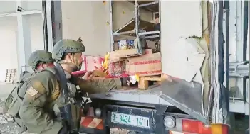  ?? X ?? This image from undated video shows Israel soldiers trying to burn food and water supplies found in the back of an abandoned truck in Gaza, one of several viral videos of Israeli soldiers behaving inappropri­ately that have emerged in recent days.