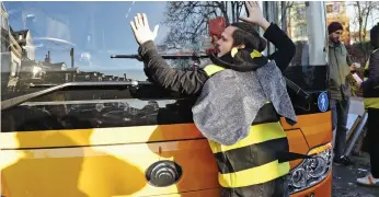 ??  ?? Hands-on approach: A protester glues himself to the front of the electric bus
