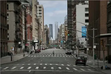  ?? WONG MAYE-E — THE ASSOCIATED PRESS ?? A cyclist rides his bicycle down the middle of a main road March 22in downtown New York City. The mayor prepared to order his city behind closed doors in an attempt to slow a pandemic that has swept across the globe and threatened to make the city of 8.5million one of the world’s biggest coronaviru­s hot spots.