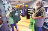  ??  ?? Sylvia Smith, left, and her father, David Smith, of Rifle, Colo., select T-shirts at Alien Zone in Roswell. Roswell is expecting as many as 30,000 visitors during the upcoming 2017 UFO Festival.