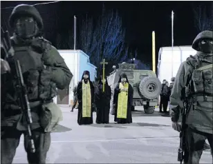  ?? — GETTY IMAGES ?? Priests stand among pro-Russia armed men blocking access to the Ukrainian frontier guard base near Sevastopol on Saturday.