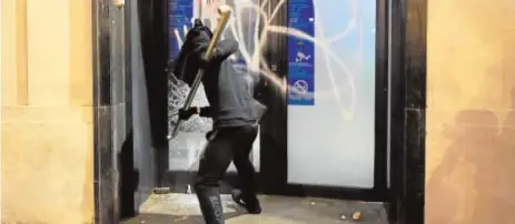  ?? AFP ?? Un encapuchad­o destroza ayer la puerta de un banco en el centro de Barcelona