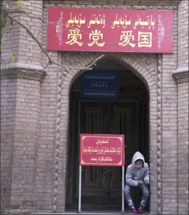  ?? AP file photo ?? A child rests near the entrance to the mosque where a banner in red reads “Love the party, Love the country” last year in the old city district of Kashgar in western China’s Xinjiang region. Since 2016, Chinese authoritie­s in the heavily Muslim region...