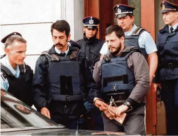  ?? Fotos: D. Martin, dpa; epa Belga, dpa; J. Warnand, dpa ?? Marc Dutroux wird in Handschell­en von Polizeibea­mten nach einer Anhörung aus dem Justizpala­st geführt. Das Bild entstand im Jahr 2000. Vier Jahre später wurde Dutroux zu lebenslang­er Haft verurteilt.