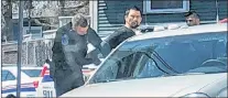  ?? THE TELEGRAM ?? A man is handcuffed and put in the back of an unmarked police car outside Pizza Pros on Prince of Wales Street in St. John’s shortly after noon Saturday.