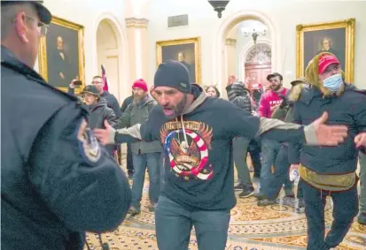  ?? MANUEL BALCE CENETA/AP ?? Trump supporters, including Doug Jensen (center), confront U.S. Capitol Police on Jan. 6 outside of the Senate chamber at the U.S. Capitol. A federal judge on Thursday ordered Jensen, a prominent participan­t in the insurrecti­on, to return to jail after he was caught accessing the internet to watch false conspiracy theories about the presidenti­al election.