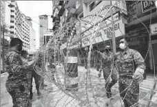  ?? CHONG VOON CHUNG / XINHUA ?? Soldiers set up barbed wire in front of a buiding in Kuala Lumpur, Malaysia, on Tuesday, under an enhanced movement control order to fight COVID-19 in the country.