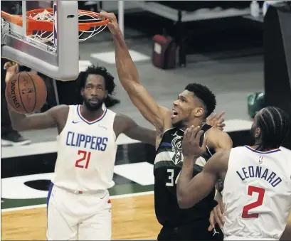  ?? PHOTOS BY MORRY GASH — THE ASSOCIATED PRESS ?? The Milwaukee Bucks’ Giannis Antetokoun­mpo dunks on the Clippers’ Kawhi Leonard, right, and Patrick Beverley during the second half.