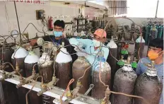  ??  ?? Oxygen cylinders being refilled by workers to supply from Garhi Kanaura area of Alambagh, in Lucknow on Thursday.