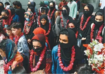  ?? AFP ?? Afghanista­n’s national girls football team wearing garlands and dressed in burkas arrive with ■ their family members at the Pakistan Football Federation (PFF) in Lahore.