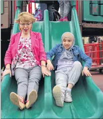  ?? ANDREW WATERMAN/SPECIAL TO THE TELEGRAM ?? Minister of Children, Seniors and Social Developmen­t Lisa Dempster tests the new slides with student Hadie Haziri.