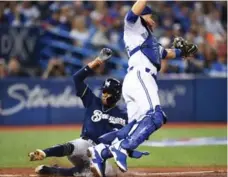  ?? FRANK GUNN/THE CANADIAN PRESS ?? The Brewers’ Keon Broxton slides safely into home past Jays catcher Russell Martin during third-inning play Tuesday night at the Rogers Centre.