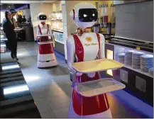  ?? PETER DEJONG / ASSOCIATED PRESS ?? Leah Hu (left) and brother Leon demonstrat­e the use of robots for serving purposes or for dirty dishes at the Royal Palace restaurant in southweste­rn Netherland­s.