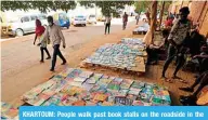  ??  ?? KHARTOUM: People walk past book stalls on the roadside in the Sudanese capital on Jan 14, 2021. —AFP