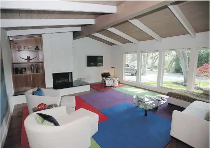 ??  ?? The living room’s vaulted ceiling is original, but the hearth was expanded to reach the wall and topped in black granite. Toronto interior designer Rodney Deeprose envisioned the shelving unit and multi-colour geometric carpet.